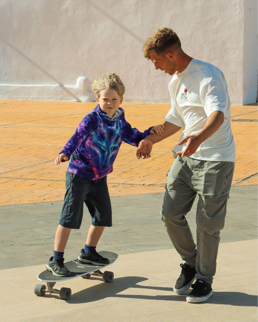 Instruktör André hjälper ett barn under en surfskate-lektion.